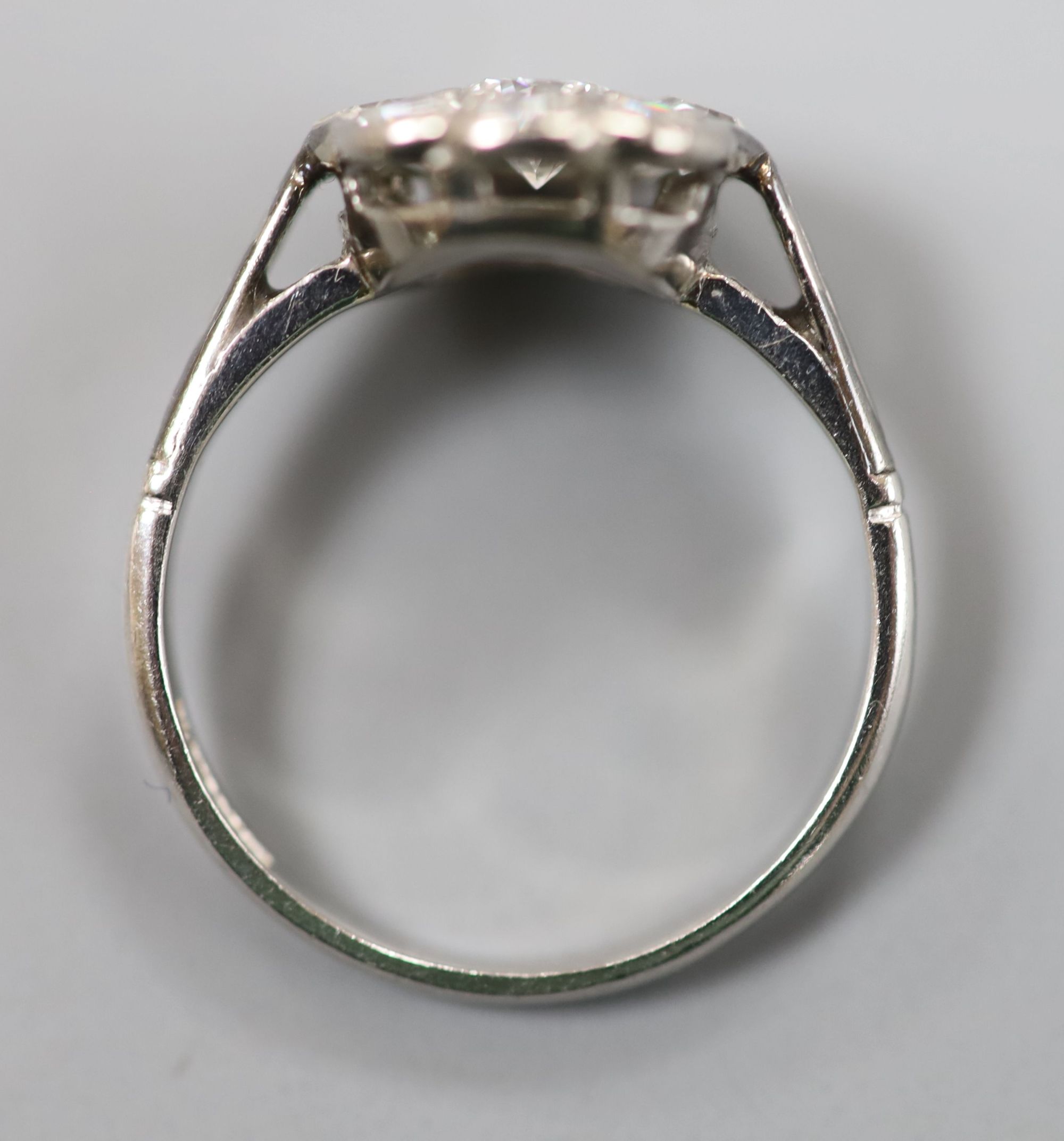 A mid 20th century white metal (stamped platinum) and nine-stone diamond set cluster ring, size K, gross 3 grams.